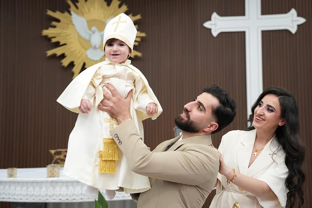Parents lifting their child in joy at a Melbourne baptism