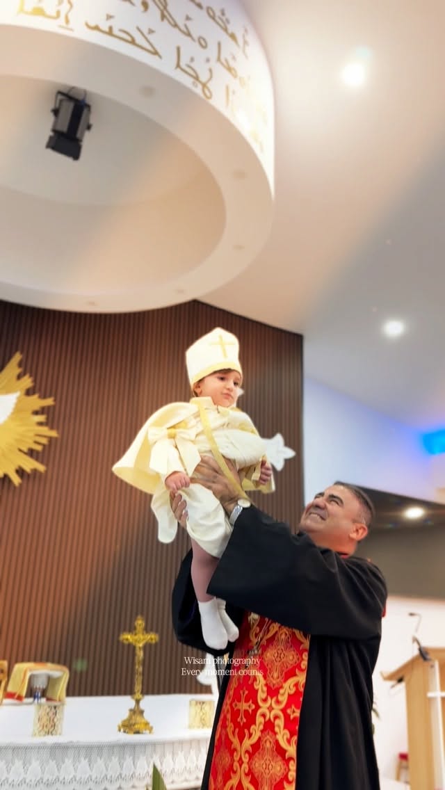 Priest lifting a baby during baptism